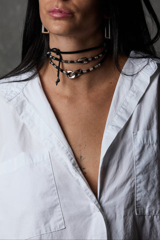Woman wearing multiple necklaces with a plain background